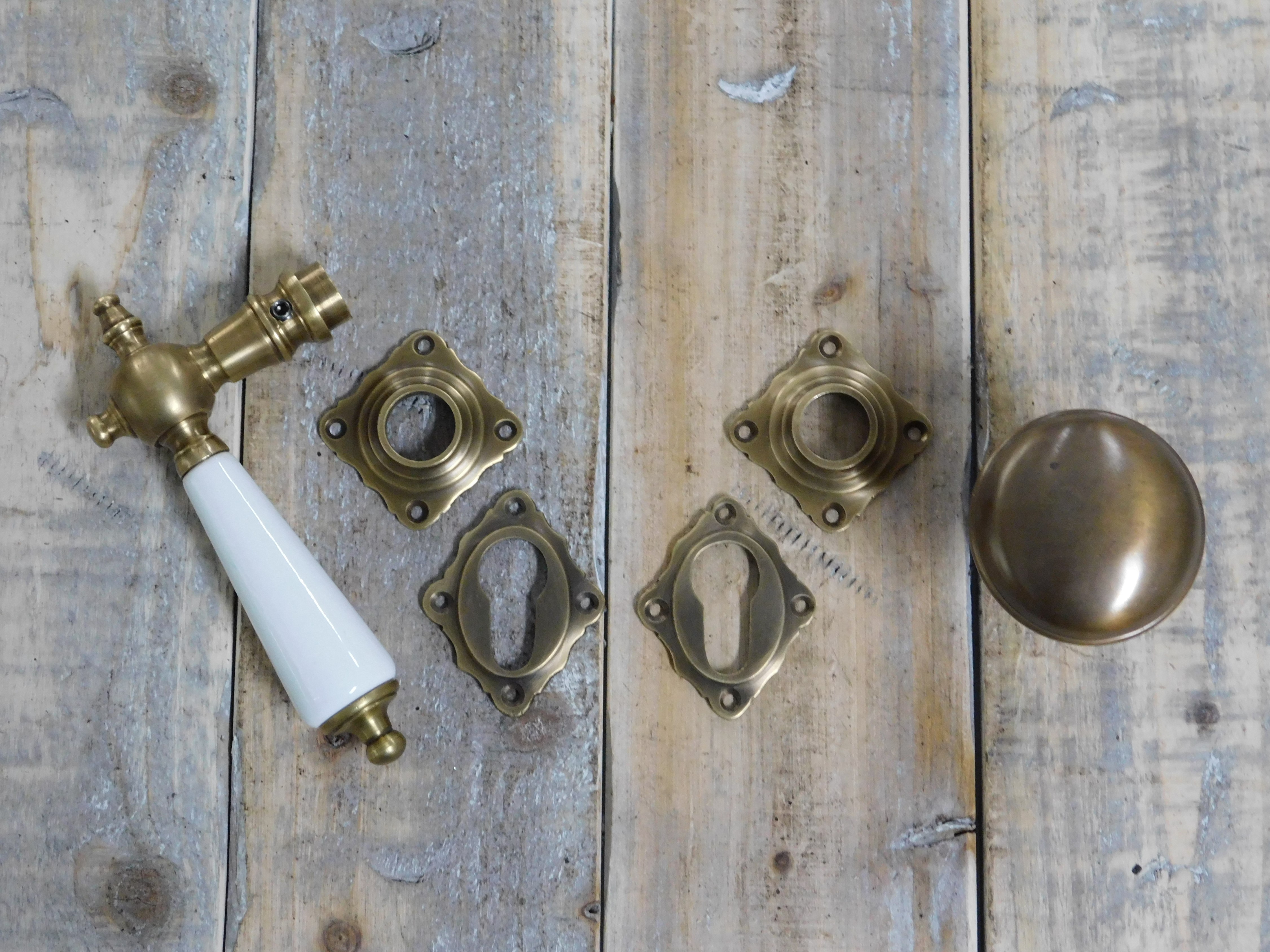 Set deurbeslag: 1 deurklink + 1 deurknop en 4 rozetten, gepatineerd messing met porselein in kleur, voor voordeuren