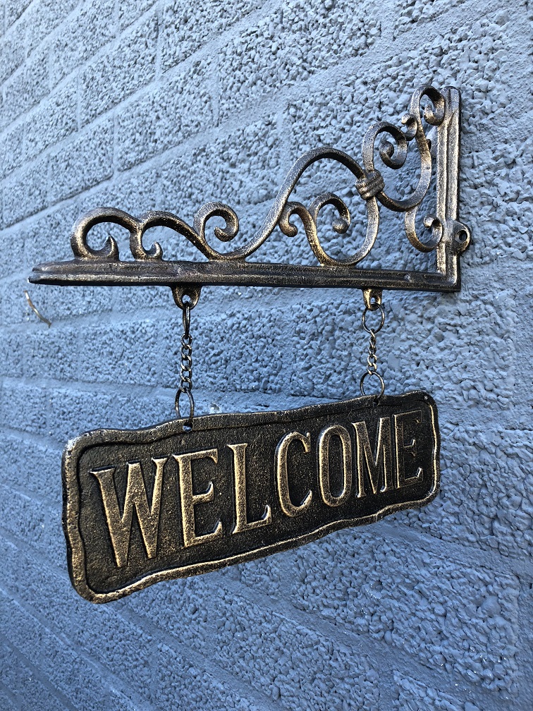 Uithangbord-wandbord aan mooie handbeugel, metaal, bronskleur, met de tekst: WELCOME.