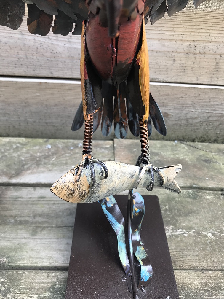 Een metalen kunstwerk van een adelaar die een vis vangt, ''IRON EAGLE''
