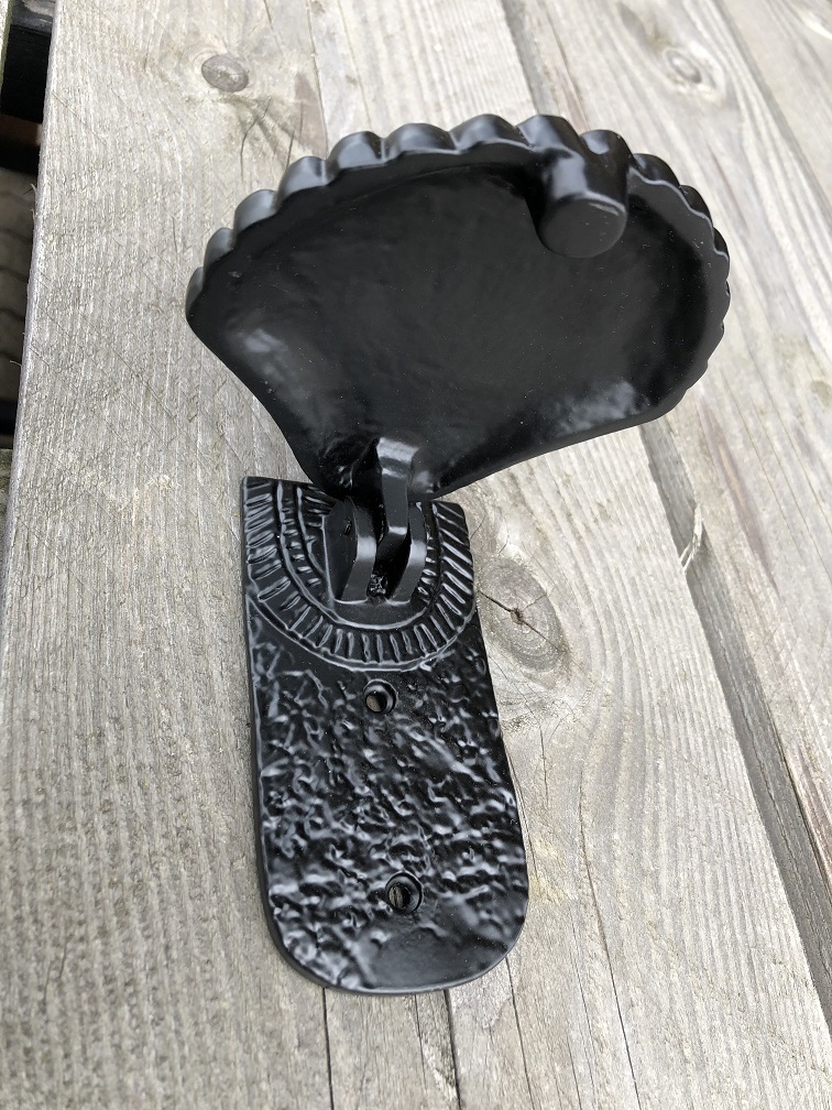 Dekorativer Türklopfer in Form einer Muschel, ganz aus schwarzem Metall.