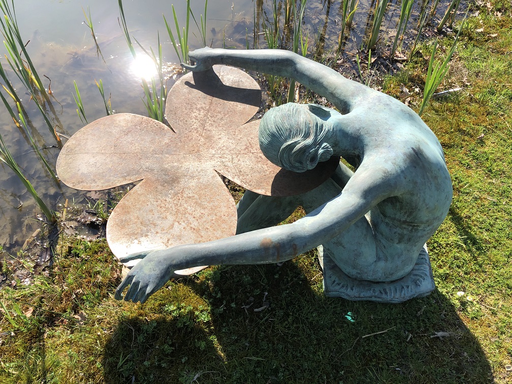 Bronzen naakte dame rustend op een lelieblad aan de vijverrand.