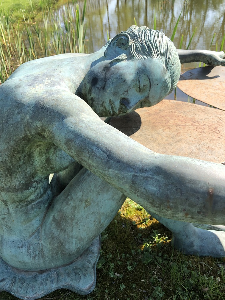Bronzen naakte dame rustend op een lelieblad aan de vijverrand.