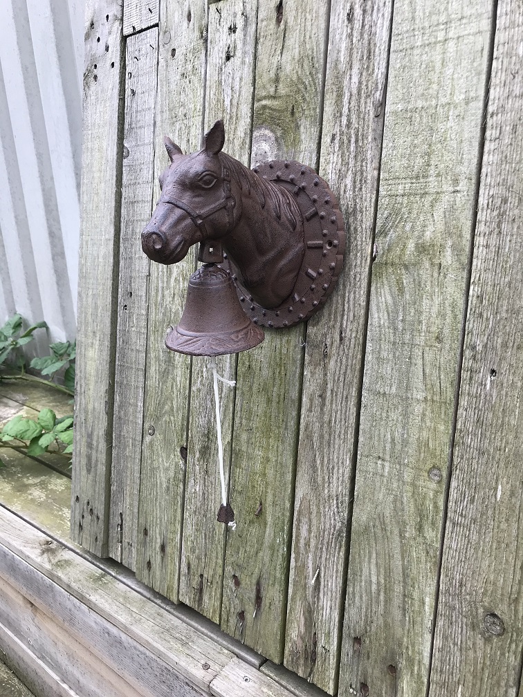 Een mooie deurbel met paardenhoofd gevestigd op een fraaie achtergrond, heel leuk!