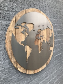 Een groot wandornament, gemaakt van hout met hierop een wereld, zee van metaal