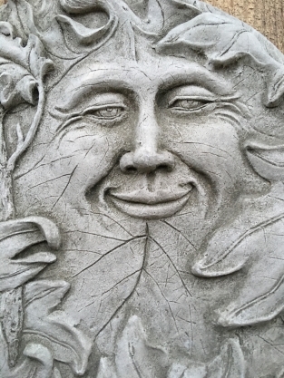 Wall ornament stone round, with an image of the cheerful oak leaf man, forest spirit.