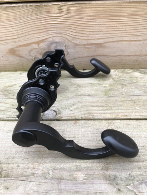Mooi zwart metalen deurbeslagset, met geveerde sluiting op de rozetten.
