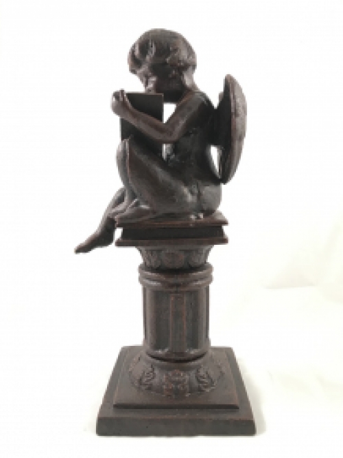 Intact statue of an angel sitting on a pedestal writing, cast iron