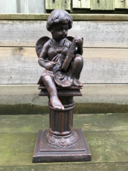 Intact statue of an angel sitting on a pedestal writing, cast iron