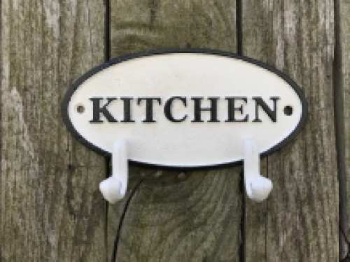 Een kapstok met 2 haken, bord met opschrift: ''KITCHEN'' als achtergrond, gietijzer
