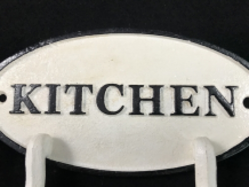Een kapstok met 2 haken, bord met opschrift: ''KITCHEN'' als achtergrond, gietijzer