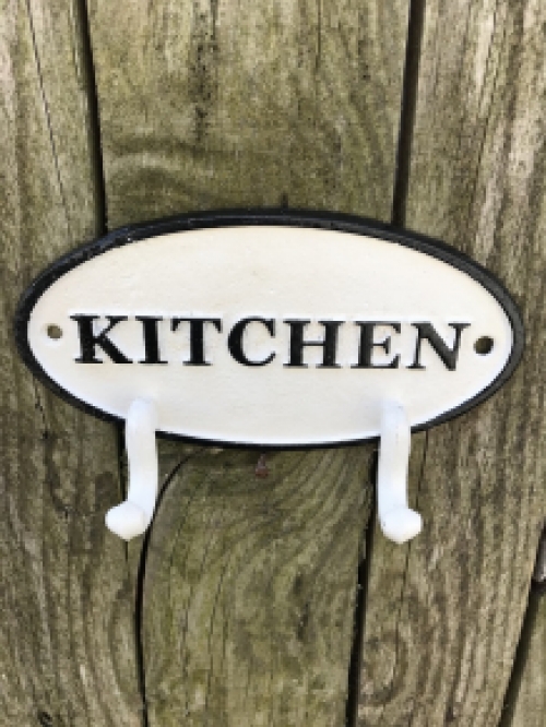 Een kapstok met 2 haken, bord met opschrift: ''KITCHEN'' als achtergrond, gietijzer