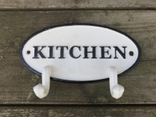 Een kapstok met 2 haken, bord met opschrift: ''KITCHEN'' als achtergrond, gietijzer