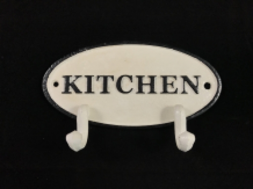 Een kapstok met 2 haken, bord met opschrift: ''KITCHEN'' als achtergrond, gietijzer
