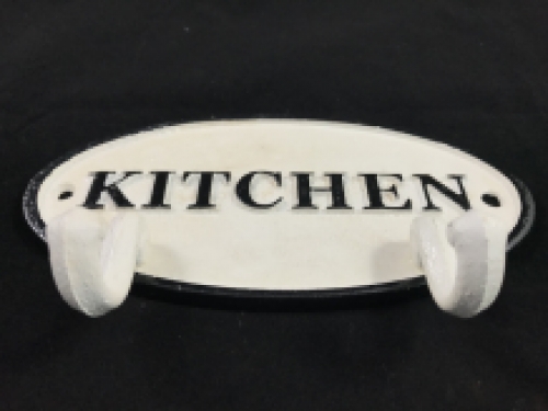 Een kapstok met 2 haken, bord met opschrift: ''KITCHEN'' als achtergrond, gietijzer