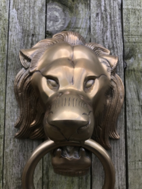 Een leeuwenkop, gemaakt van aluminium in messing kleur, als deurklopper