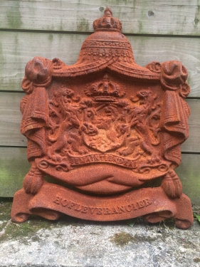 Gietijzeren wandornament, zwaar uitgevoerd met de spreuk: Je maintiendrai (ik zal handhaven), hofleverancier