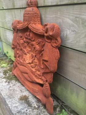 Gietijzeren wandornament, zwaar uitgevoerd met de spreuk: Je maintiendrai (ik zal handhaven), hofleverancier