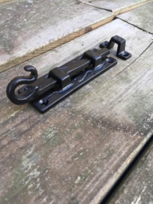 Een fraaie deurgrendel, mat zwart, gemaakt van smeedijzer