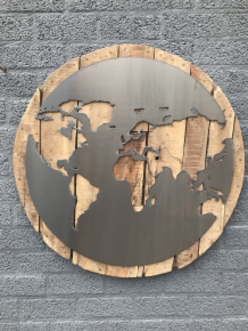 Een groot wandornament, gemaakt van hout met hierop een wereld, zee van metaal