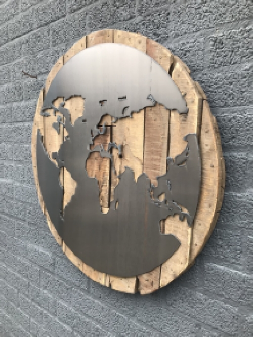 Een groot wandornament, gemaakt van hout met hierop een wereld, zee van metaal