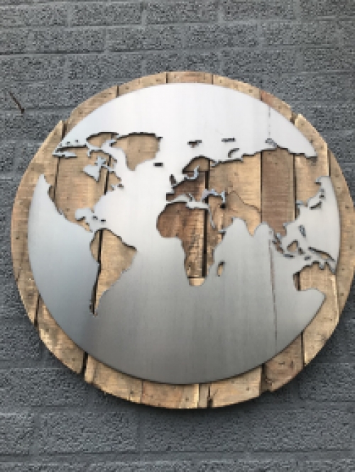 Een groot wandornament, gemaakt van hout met hierop een wereld, zee van metaal