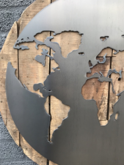 Een groot wandornament, gemaakt van hout met hierop een wereld, zee van metaal