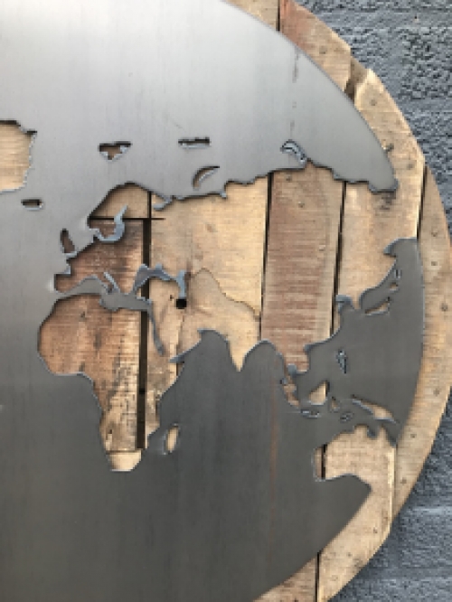Een groot wandornament, gemaakt van hout met hierop een wereld, zee van metaal