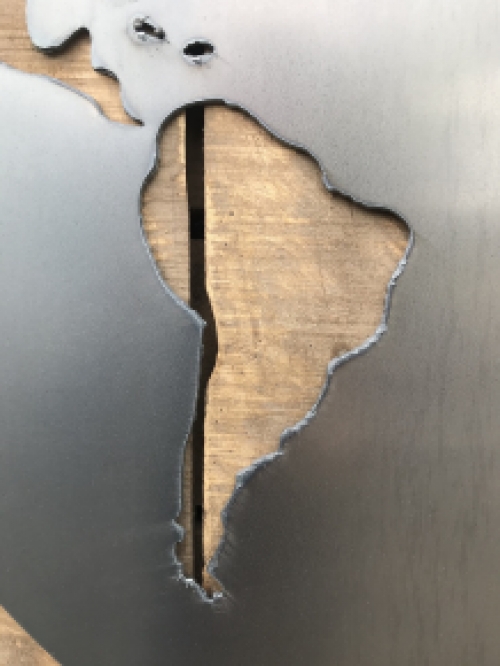 Een groot wandornament, gemaakt van hout met hierop een wereld, zee van metaal