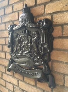 Zwaart gietijzeren wandornament, zwaar uitgevoerd met de spreuk: Je maintiendrai (ik zal handhaven), hofleverancier